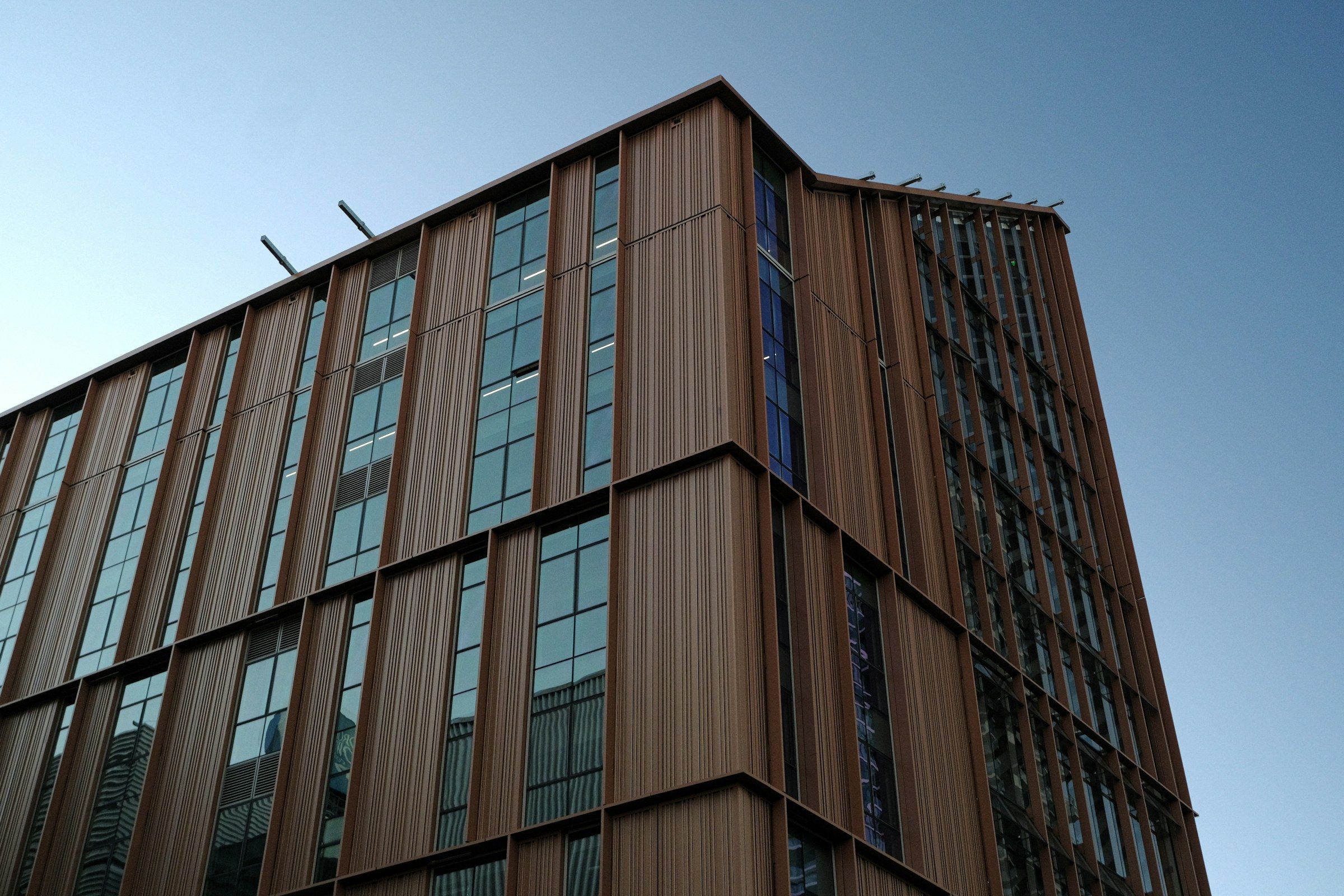 Multi-storey building with a vertical timber façade, seen from below